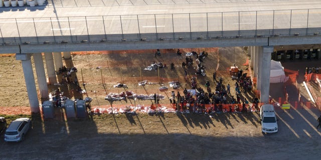 In this photo taken by a drone, migrants are seen in custody at a U.S. Customs and Border Protection processing area under the Anzalduas International Bridge, Thursday, March 18, 2021, in Mission, Texas. . (AP Photo/Julio Cortez)