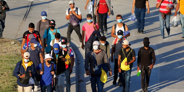 Migrants who aim to reach the U.S. walk along a highway as they leave San Pedro Sula, Honduras, early Tuesday, March 30, 2021. As the Biden administration deals with a new surge of migrants, a task force it set up has begun reuniting some migrant families that were separated under a previous Trump administration policy. (AP Photo/Delmer Martinez)