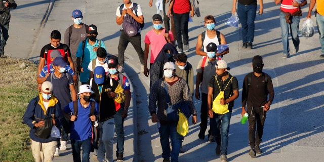 Migrants who aim to reach the U.S. walk along a highway as they leave San Pedro Sula, Honduras, early Tuesday, March 30, 2021. As the Biden administration deals with a new surge of migrants, a task force it set up has begun reuniting some migrant families that were separated under a previous Trump administration policy. (AP Photo/Delmer Martinez)