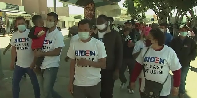 Migrants at the southern border wear shirts asking President Biden to let them into the U.S.