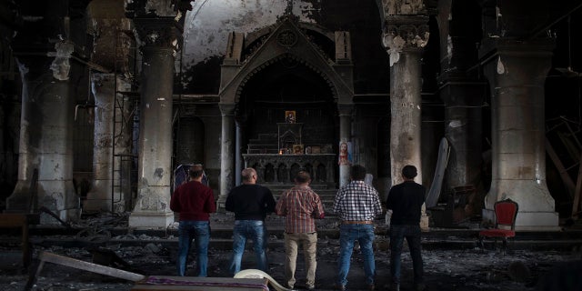 In this November 2016 photo, Iraqi Christians pray at the Church of the Immaculate Conception, damaged by Islamic State fighters during their occupation of Qaraqosh, east of Mosul, Iraq. (AP)