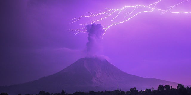 The long-time exposure photo taken on March 5, 2021 shows lightning striking near Mount Sinabung with white smoke being spewed in Karo, North Sumatra, Indonesia. (Photo by Sarianto Sembiring/Xinhua via Getty) 