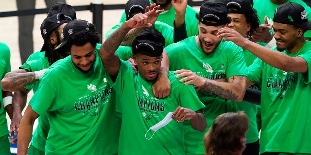 North Texas guard Javion Hamlet, center, celebrates with teammates after the championship game against Western Kentucky in the NCAA Conference USA men's basketball tournament Saturday, March 13, 2021, in Frisco, Texas. North Texas won 61-57 in overtime. (AP Photo/Tony Gutierrez)