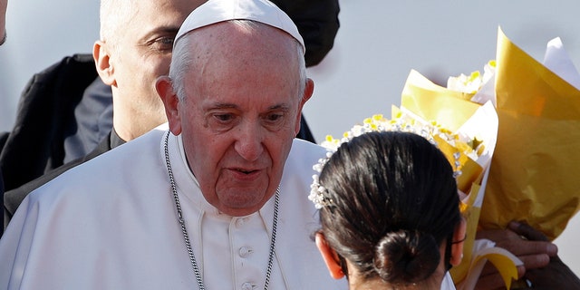 Children give Pope Francis, center, flowers as he arrives at Irbil International Airport, Iraq, Sunday, March 7, 2021. Francis is urging Iraq’s long-suffering Christians to forgive the injustices committed against them by Muslim extremists. He asks them to persevere to rebuild the country after years of war and sectarian conflicts. (AP Photo/Hadi Mizban)