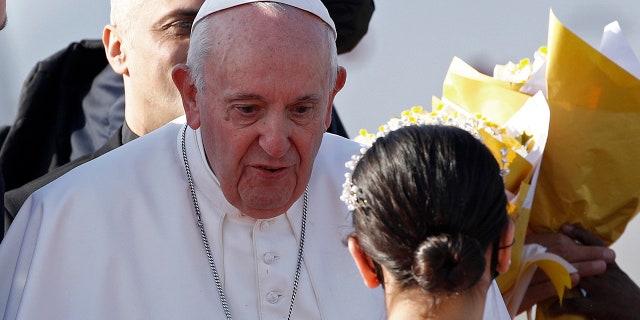 Children give Pope Francis, center, flowers as he arrives at Irbil International Airport, Iraq, Sunday, March 7, 2021. Francis is urging Iraq’s long-suffering Christians to forgive the injustices committed against them by Muslim extremists. He asks them to persevere to rebuild the country after years of war and sectarian conflicts. (AP Photo/Hadi Mizban)