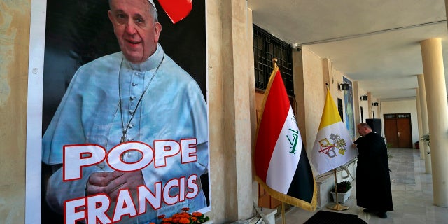 Father Nazeer Dako arranges a Vatican flag to welcome Pope Francis at St. Joseph's Chaldean Church ahead of the Pope's visit, in Baghdad, Iraq, on Tuesday. (AP)