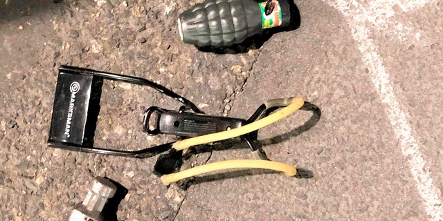 This Friday, March 12, 2021, photo shows numerous items left behind by people inside the perimeter of a march, including, high impact slingshot, and knives, after they corralled a group of about 100 hundred protesters Friday night in Portland, Ore. (Portland Police Department via AP)