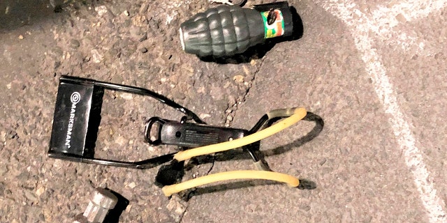 This Friday, March 12, 2021, photo shows numerous items left behind by people inside the perimeter of a march, including, high impact slingshot, and knives, after they corralled a group of about 100 hundred protesters Friday night in Portland, Ore. (Portland Police Department via AP)