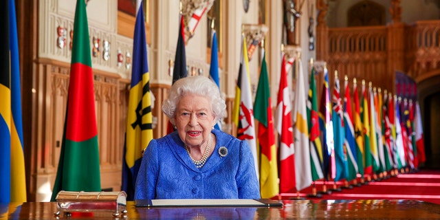 In this photo made available Sunday March 7, 2021, Britain's Queen Elizabeth II poses for a photo while signing her annual Commonwealth Day Message inside St George's Hall at Windsor Castle, England, Friday March 5, 2021.