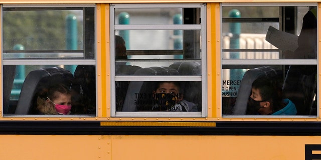 FILE - In this Thursday, Nov. 19, 2020, file photo, elementary school students sit on board a school bus after attending in-person classes at school in Wheeling, Ill. (AP Photo/Nam Y. Huh, File)