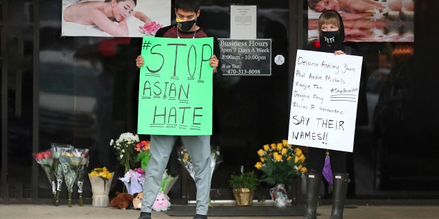 After dropping off flowers Jesus Estrella, left, and Shelby stand in support of the Asian and Hispanic community outside Young's Asian Massage Wednesday, March 17, 2021, in Acworth, Ga.