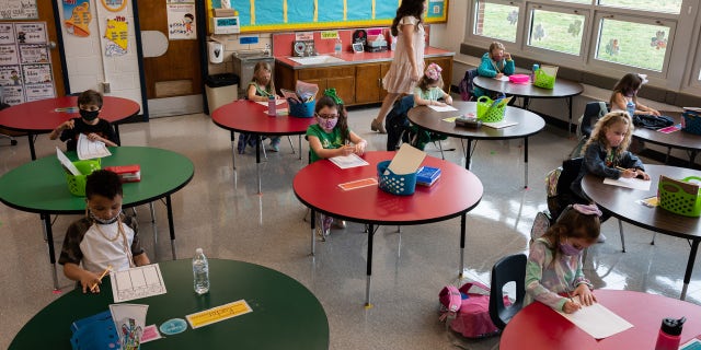 A teacher walks among the masked students sitting in a socially distanced classroom session at Medora Elementary School.