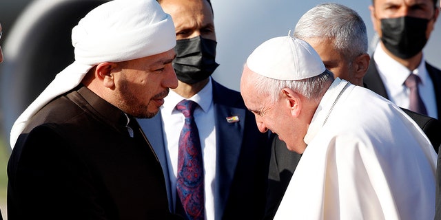 Pope Francis, right, is welcomed by Muslim clerics as he arrives at the Irbil international airport, Iraq, Sunday, March 7, 2021. (Associated Press)