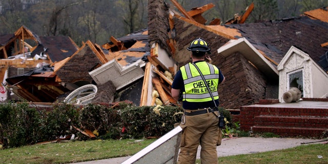 A firefighter surveys damage to a house where the family was trapped, but were able to get out after a tornado touches down south of Birmingham, Ala. in the Eagle Point community damaging multiple homes Thursday, March 25, 2021.