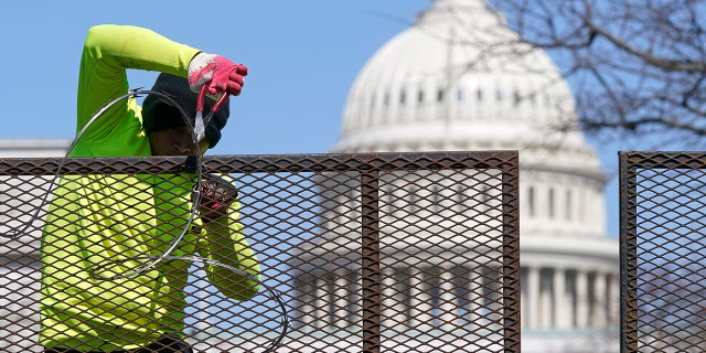 A worker removes razor wire from a security fence on Capitol Hill in Washington, Saturday, March 20, 2021. (AP Photo/Patrick Semansky)