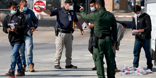 Des agents des douanes et de la protection des frontières américaines, au centre, ordonnent à un migrant de marcher vers le pont international McAllen-Hidalgo tout en les expulsant vers le Mexique, samedi 20 mars 2021, à Hidalgo, au Texas.  (Photo AP / Julio Cortez)