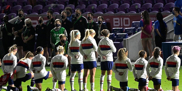 Some members of the United States team kneel during the playing of the national anthem before a SheBelieves Cup women's soccer match against Canada, Thursday, Feb. 18, 2021, in Orlando, Fla. (AP Photo/Phelan M. Ebenhack)