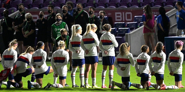 Some members of the United States team kneel during the playing of the national anthem before a SheBelieves Cup women's soccer match against Canada, Thursday, Feb. 18, 2021, in Orlando, Fla. (AP Photo/Phelan M. Ebenhack)