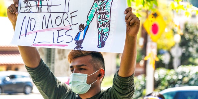 A man holds a sign at the "Reunite Our Families Now!'' rally to protest continued deportations, demanding family and children reunifications in Los Angeles, March 6, 2021. (AP Photo/Damian Dovarganes)