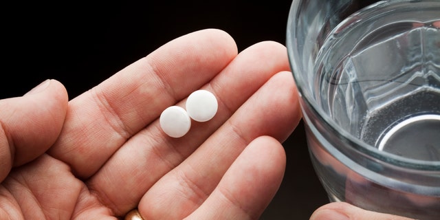 Aspirin pills in person's hand