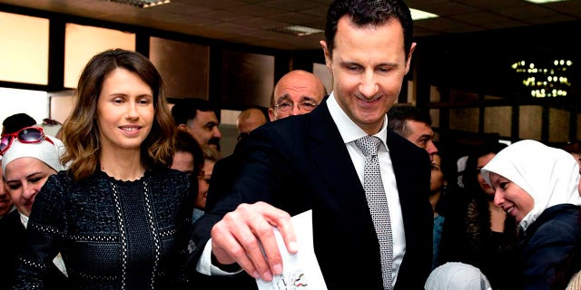 Syrian President Bashar Assad casts his ballot in the parliamentary elections, as his wife Asma, stands next to him, in Damascus, Syria.