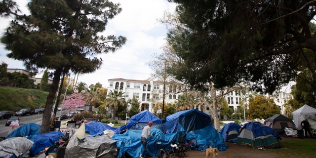 Valerie Zeller and her dog Redd both stand outside their tent in Echo Park Lake on Saturday, March 20, 2021, in Los Angeles, CA.(Francine Orr / Los Angeles Times via Getty Images)