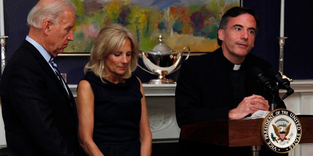 In this Nov. 22, 2010, file photo, Vice President Joe Biden, left, and his wife, Jill Biden, center, stand with heads bowed as the Rev. Kevin O'Brien says the blessing during a Thanksgiving meal for Wounded Warriors in Washington. (AP Photo/Carolyn Kaster, File)
