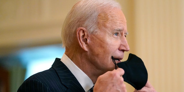 President Joe Biden removes his face mask as he arrives to speak about COVID-19 vaccinations, from the East Room of the White House, Thursday, March 18, 2021, in Washington. (AP Photo/Andrew Harnik)