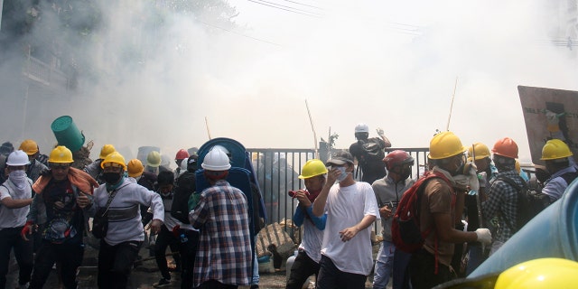 Smoke from tear gas launched by security forces rises near protesters during an anti-coup protest in Mandalay, Burma, Tuesday, March 2, 2021. Demonstrators in Burma took to the streets again on Tuesday to protest last month’s seizure of power by the military, as foreign ministers from Southeast Asian countries prepared to meet to discuss the political crisis. (AP Photo)