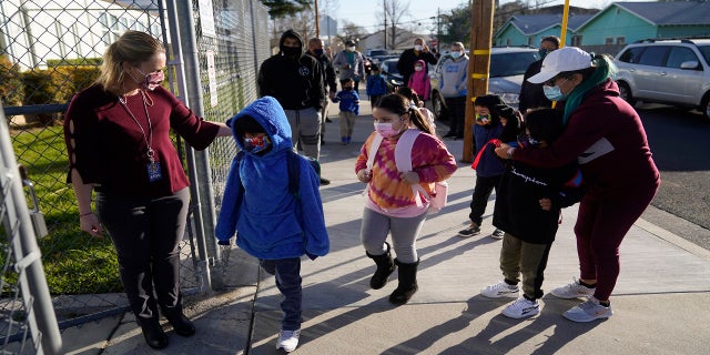 Assistant Principal Janette Van Gelderen, left, welcomes students at Newhall Elementary in Santa Clarita, Calif., on Feb. 25. California's public schools could get $6.6 billion from the state Legislature if they return to in-person instruction by the end of March, according to a new agreement announced Monday, between Gov. Gavin Newsom and the state's legislative leaders. (AP)