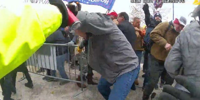Julian Elie Khater, with his right arm in the air, appears to be holding a canister in his right hand and aiming it in the officers' direction, prosecutors say.