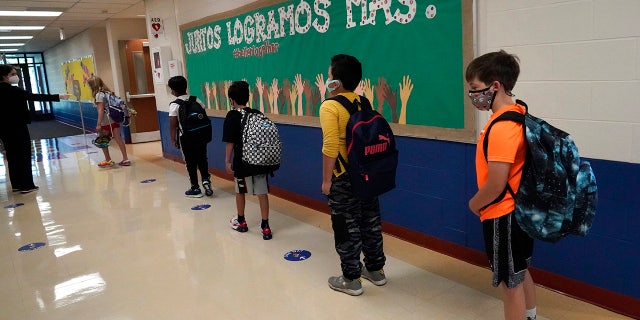 In this Sept. 3, 2020, file photo, students keep social distance as they walk to their classroom at Oak Terrace Elementary School in Highwood, Ill., part of the North Shore school district. New evidence that it may be safe for schools to seat students 3 feet apart — half of the previous recommended distance — could offer a way to return more of the nation’s children to classrooms with limited space. (AP Photo/Nam Y. Huh)