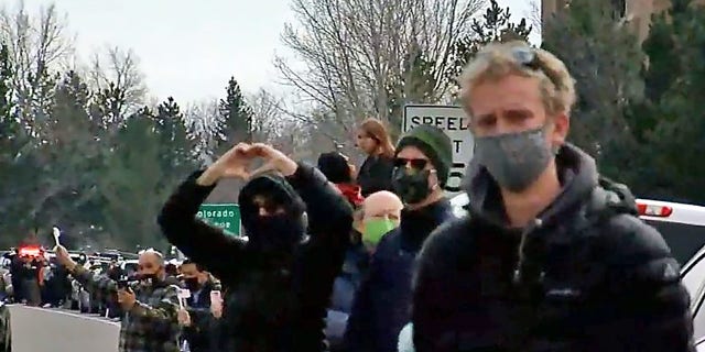 Pedestrians pay their respects Wednesday to Boulder Police Officer Eric Talley alongside a road where a police procession transferred his body to a funeral home.