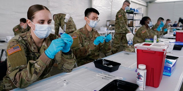 Dans cette photo d'archive du 9 mars 2021, des spécialistes de la santé de l'armée remplissent des seringues avec le vaccin Pfizer COVID-19 à Miami.