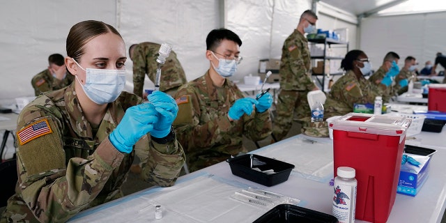 Dans cette photo d'archive du 9 mars 2021, des spécialistes de la santé de l'armée remplissent des seringues avec le vaccin Pfizer COVID-19 à Miami.