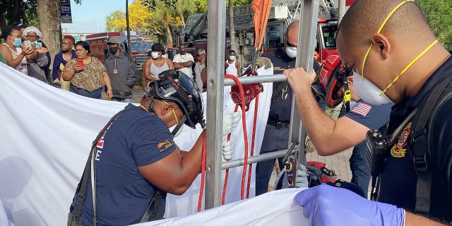First responders held up a sheet for the victim's privacy as onlookers cheered her rescue.