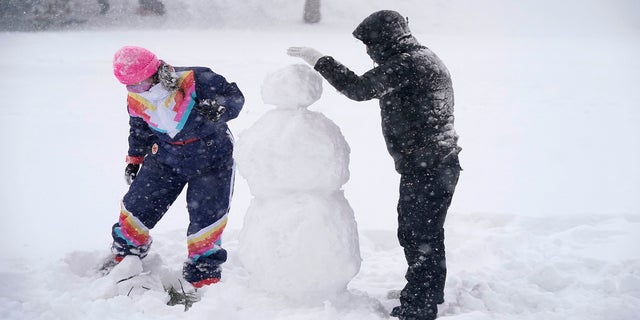 Jimmy Mundell, right, and Abbey Eilermann build a snowman as a snowstorm passed through Denver on Sunday. (AP)