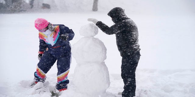 Jimmy Mundell, right, and Abbey Eilermann build a snowman as a snowstorm passed through Denver on Sunday. (AP)