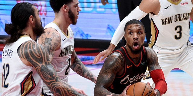 Portland Trail Blazers guard Damian Lillard, right, drives to the basket on New Orleans Pelicans guard Lonzo Ball, center, and center Steven Adams, left, during the second half of an NBA basketball game in Portland, Ore., Thursday, March 18, 2021. The Blazers won 101-93. (AP Photo/Steve Dykes)