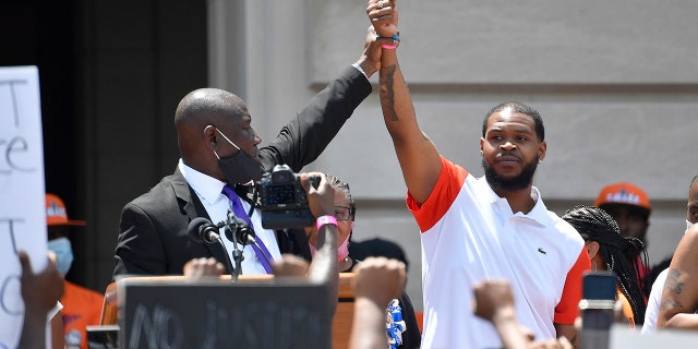 Attorney Benjamin Crump, left, holds up the hand of Kenneth Walker during a rally on the steps of the Kentucky State Capitol in Frankfort, Ky., Thursday, June 25, 2020. (AP Photo/Timothy D. Easley)