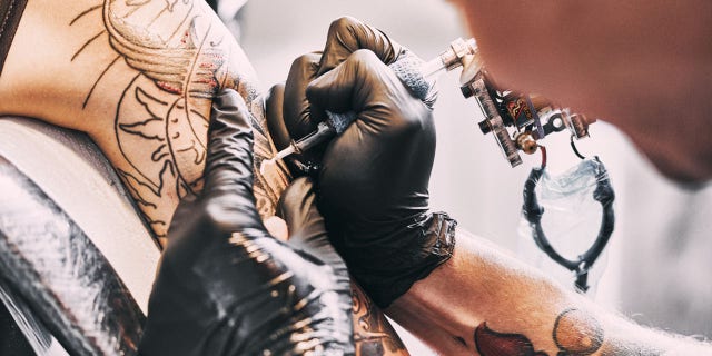 Tattoo Artist making a tattoo on a shoulder