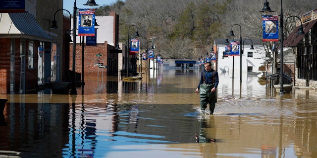 Brad Newnam crosses a flooded East Main Street while checking on businesses in the area in downtown Beattyville, Ky., on Tuesday. Heavy rains caused the Kentucky River to flood most of downtown Beattyville. (AP/Lexington Herald-Leader)