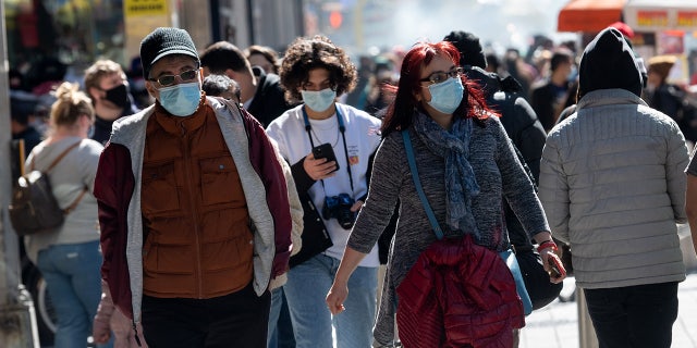 People wearing masks walk in Times Square on the first day of spring on March 20, 2021m in New York City. (Alexi Rosenfeld/Getty Images)