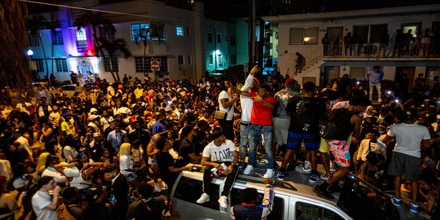 Crowds defiantly gather in the street while a speaker blasts music an hour past curfew in Miami Beach, Fla., on Sunday. An 8 p.m. curfew has been extended in Miami Beach after law enforcement worked to contain unruly crowds of spring break tourists. (AP/Miami Herald)