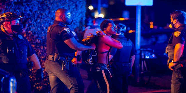 A man is arrested while out a few hours past curfew in Miami Beach, Fla., op Sondag. (AP/Miami Herald)
