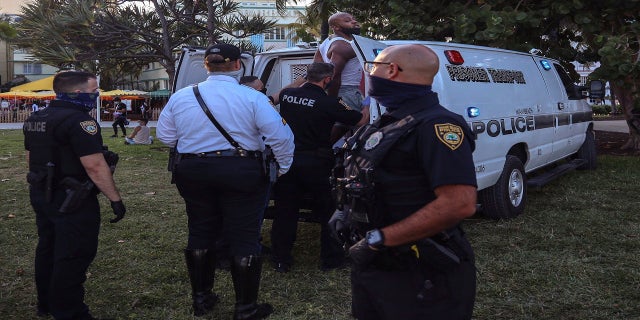 An unidentified man is detained and later arrested on Sunday at 5th Street and Ocean Drive in Miami Beach. (AP/Miami Herald)