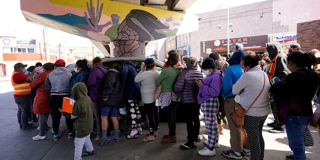 People surround a car as it arrives carrying food donations at a makeshift camp for migrants seeking asylum in the United States at the border crossing Friday, March 12, 2021, in Tijuana, Mexico. (AP Photo/Gregory Bull)