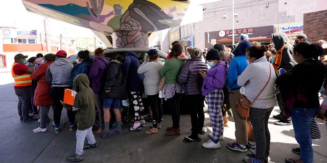 People surround a car as it arrives carrying food donations at a makeshift camp for migrants seeking asylum in the United States at the border crossing Friday, March 12, 2021, in Tijuana, Mexico. The Biden administration hopes to relieve the strain of thousands of unaccompanied children coming to the southern border by terminating a 2018 Trump-era order that discouraged potential family sponsors from coming forward to house the children. (AP Photo/Gregory Bull)