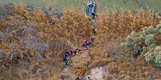 Migrant families and children climb the banks of the Rio Grande to the United States as raft smugglers prepare to return to Mexico in Penitas, Texas, United States, March 5, 2021. 