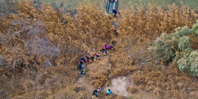 Migrant families and children climb the banks of the Rio Grande River into the United States as smugglers on rafts prepare to return to Mexico in Penitas, Texas, U.S., March 5, 2021.